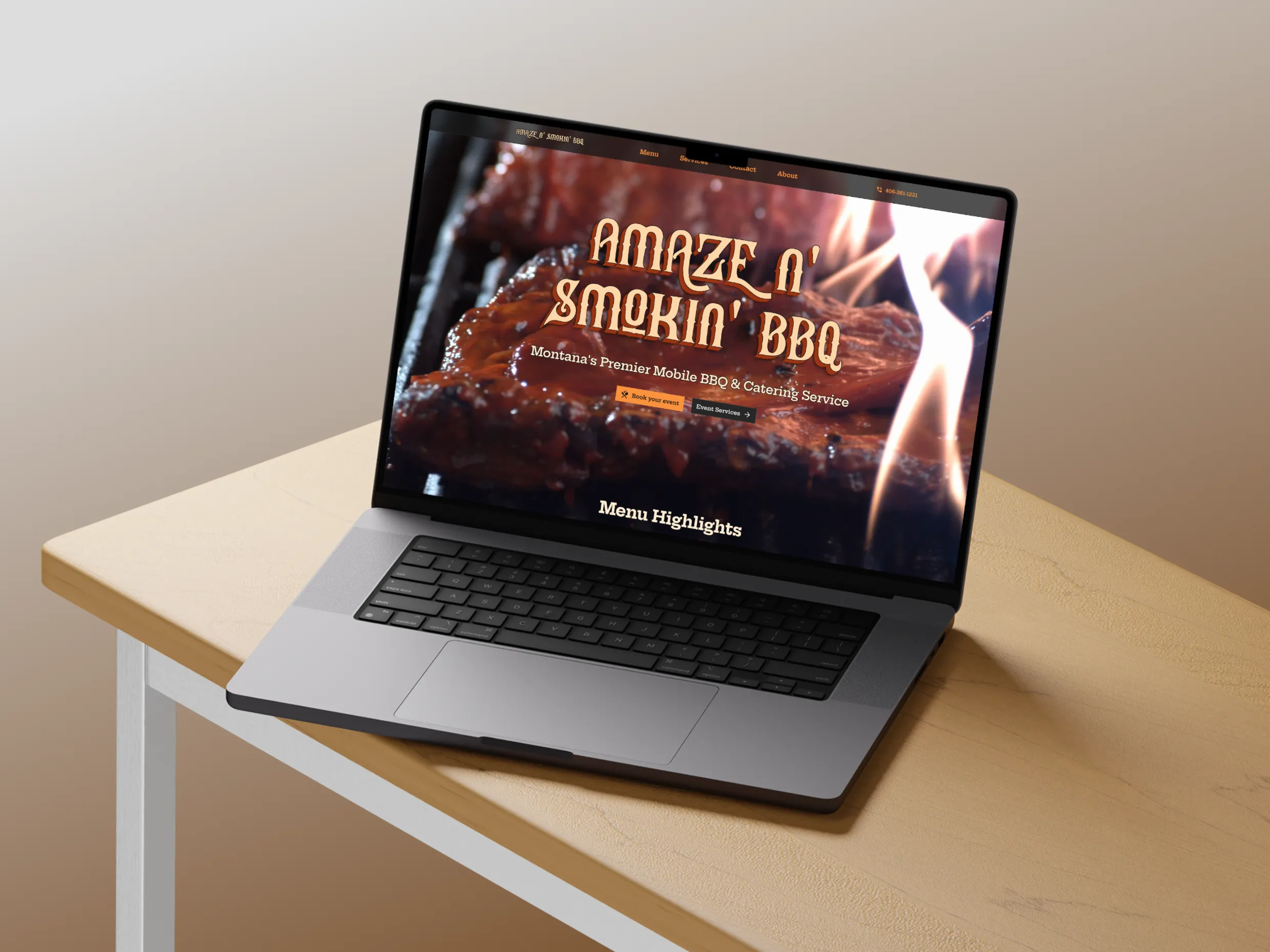 Laptop screen displaying the Amaze N' Smokin' BBQ website with a prominent image of barbecued ribs and flames in the background. The text on the screen reads "Amaze N' Smokin' BBQ Montana's Premier Mobile BBQ & Catering Service" with a button labeled "Event Services" and a menu section titled "Menu Highlights" visible below.