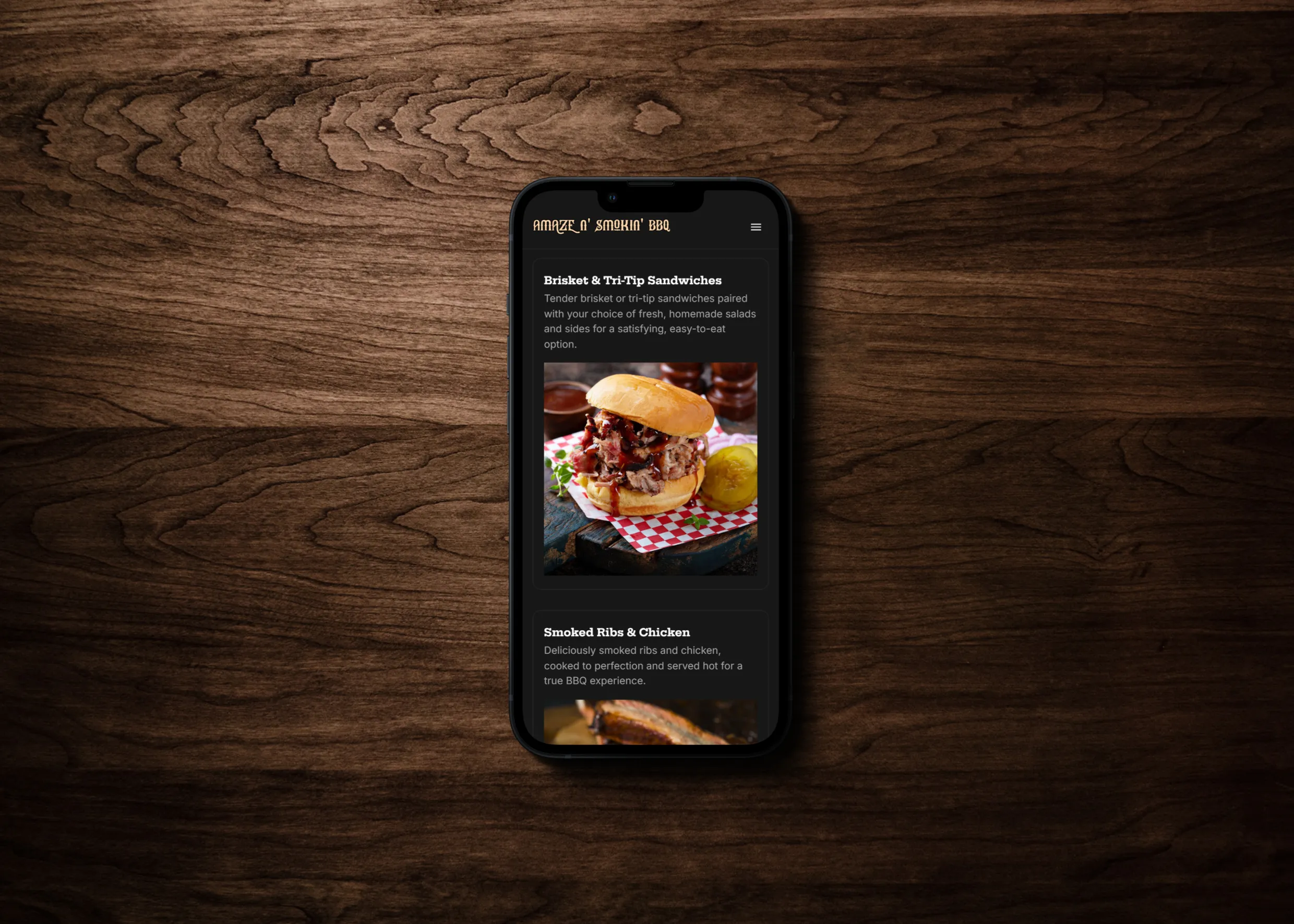 Mobile phone screen displaying the Amaze N' Smokin' BBQ website. The screen shows a menu item titled 'Brisket & Tri-Tip Sandwiches' with a description and an image of a sandwich filled with brisket and tri-tip, served on a checkered plate with sides. Below, another menu item titled 'Smoked Ribs & Chicken' is partially visible.